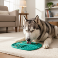 Husky dog calmly licking food from a double-sided teal green silicone slow feeder mat